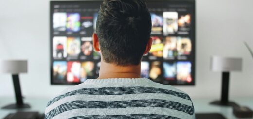 Um homem sentado à frente da TV escolhendo filmes para assistir
